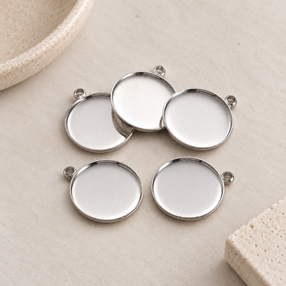 Five round stainless steel pendant settings with 20mm trays arranged on a neutral beige background.