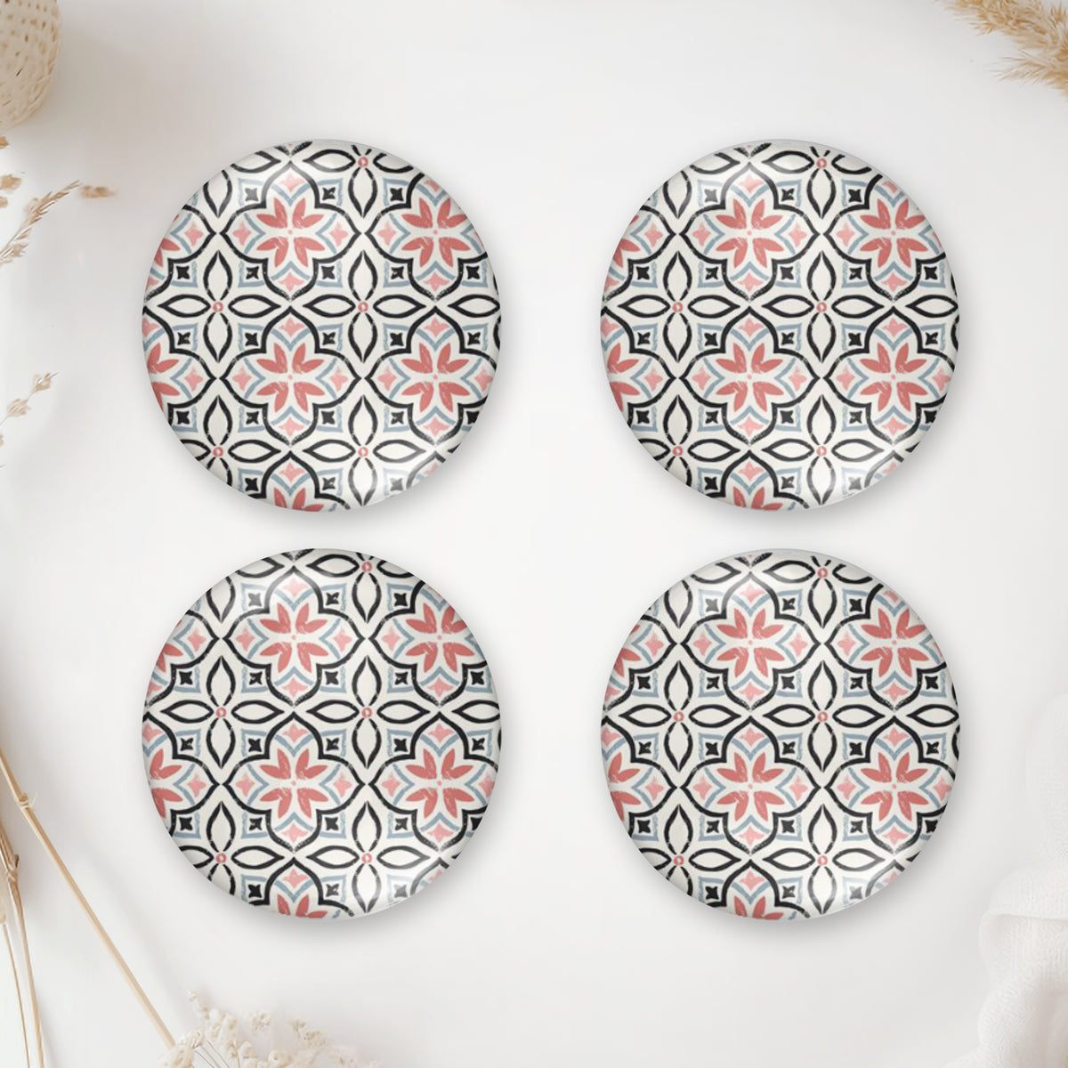 Four round handmade glass dome cabochons with a coral pink geometric tile pattern and flat backs