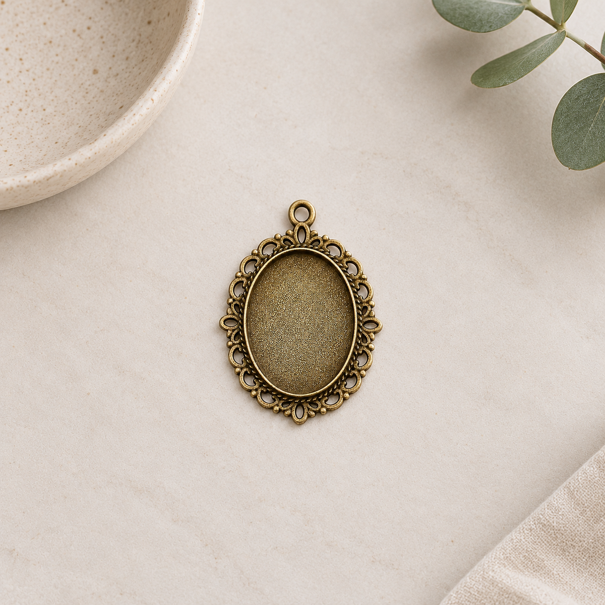 Front view of an antique bronze oval cabochon setting showing its decorative border and recessed 18x25mm tray.