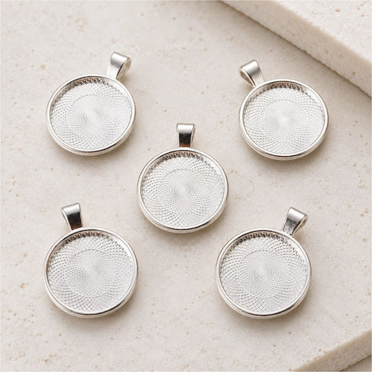 Five silver round pendant trays for 25mm cabochons, displayed on a cream background. Jewelry findings for creating DIY necklaces and handmade pendants.