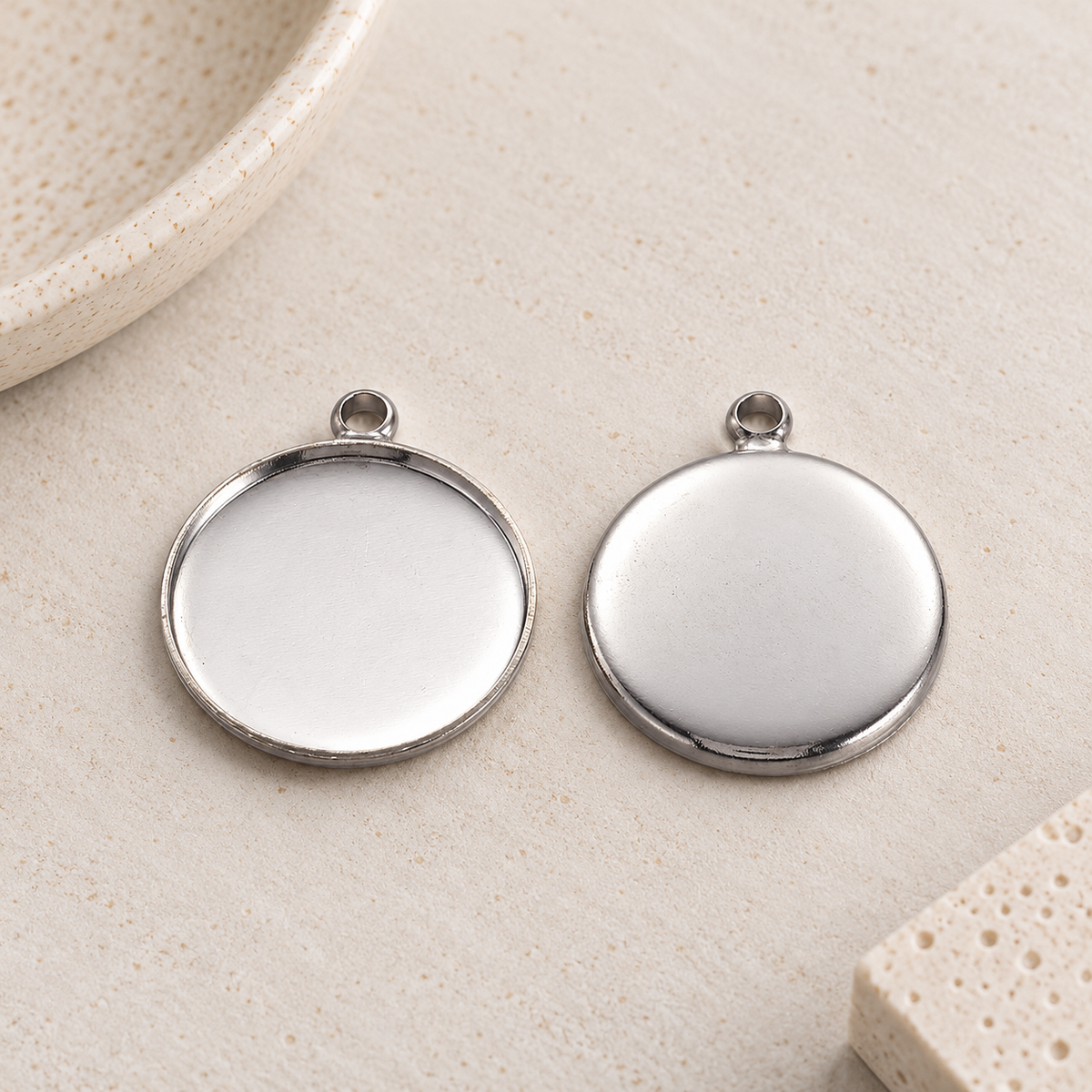 Front and back view of round silver-colored stainless steel pendant blanks for 20mm cabochons.